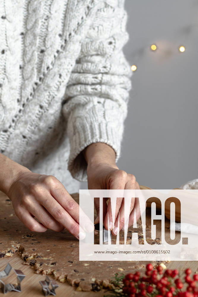Crop hands of faceless woman making gingerbread cookies with tin form in shape of star in kitchen