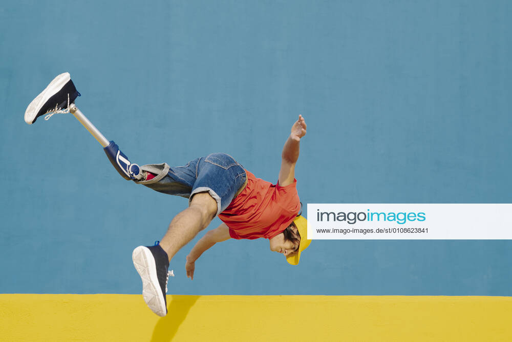 Man with artificial limb and foot jumping against multi colored wall model released Symbolfoto JCZF00271