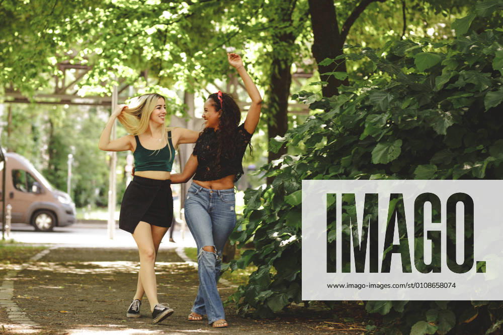 IMAGO Creative: Sommer, Sommertage im Stadtpark Cheerful women walking on green summer street in Berlin on sunny day, Model released