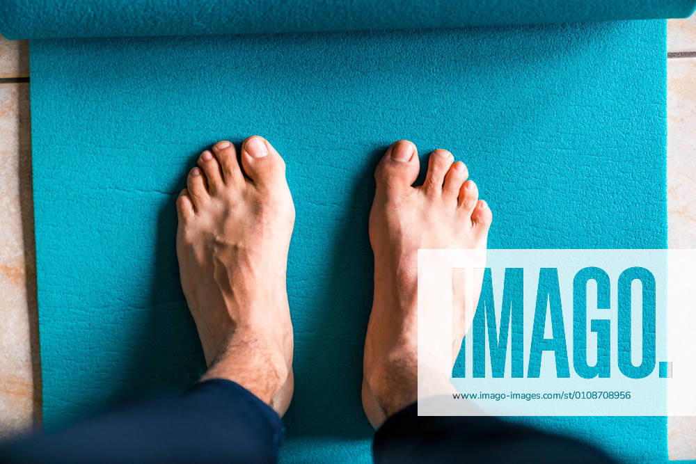 From above crop determined sportsman in active wear standing on turquoise sports mat while preparing to train in light workout room of modern fitness club