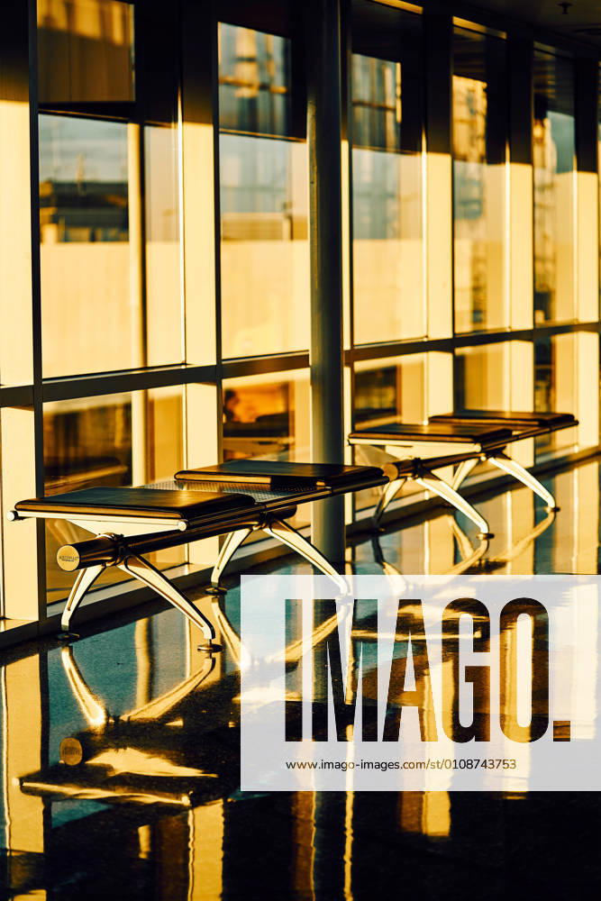 Metal bench with leather black seats along glass wall in sunny hallway of airport in Texas