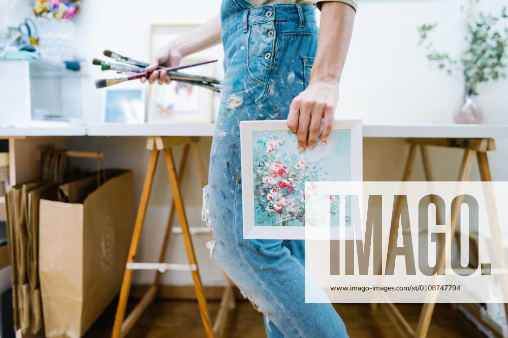 IMAGO Creative: Digitale Welt, Verzicht auf Technologie Side view of anonymous female artist standing near easel and holding a colorful paint and brushes in creative workshop