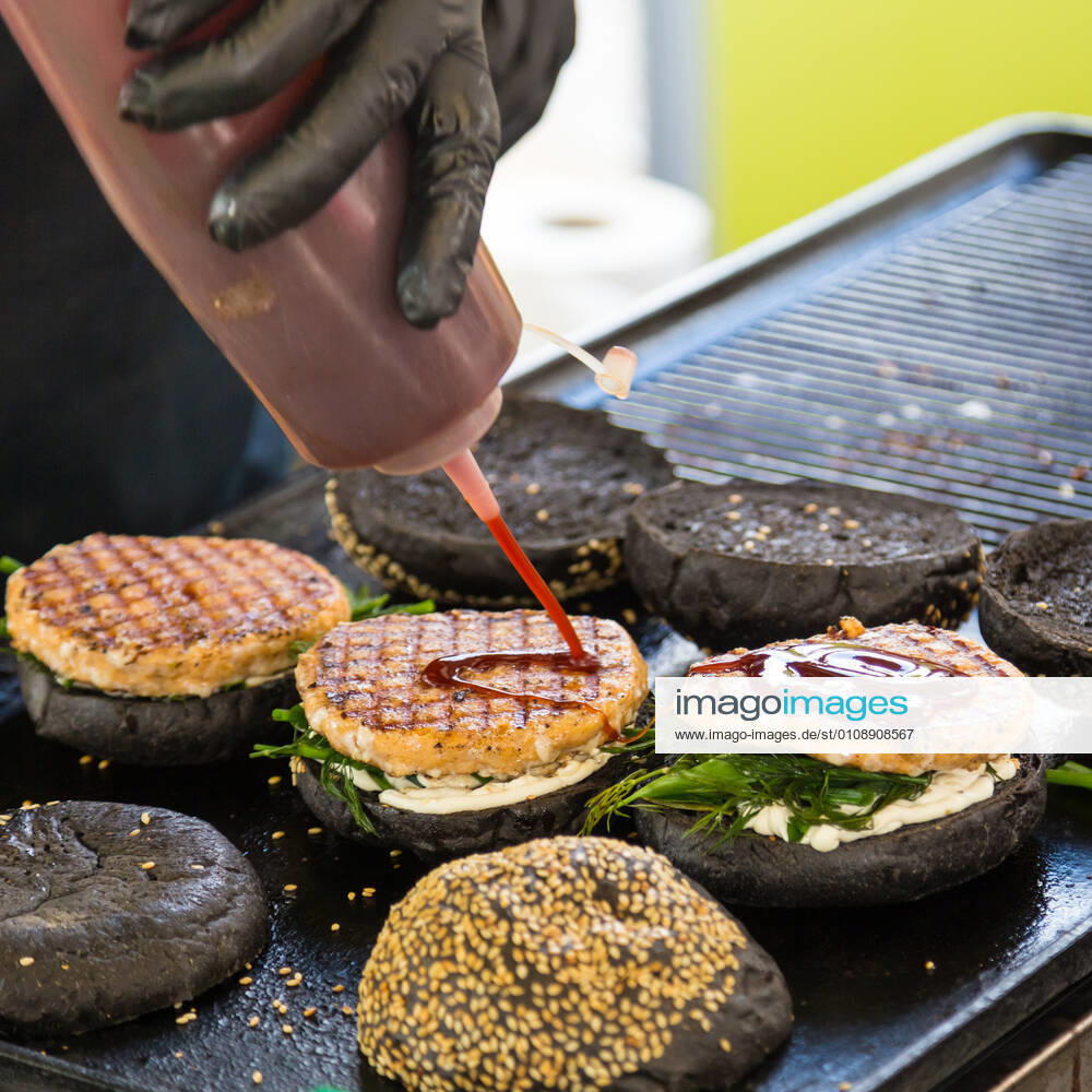 Beef burgers ready to serve on food stall. Chef making beef burgers outdoor on open kitchen international food festival event. Street food ready to serve on a food stall.burger, food, stall, hamburger, street, street food, beef, bun, fast, meat, snack, outdoors, cuisine, seller, vendor, catering, lunch, meal, delicious, restaurant, junk food, sauce, salad, outdoor, urban, event, making, chef, desk, decorate, tomatoes, sandwich, to go, take out, cart, grill, plate, dressing, ketchup, mayonnaise, lettuce, gloves, black, wholemeal, healthy, city, open kitchen,