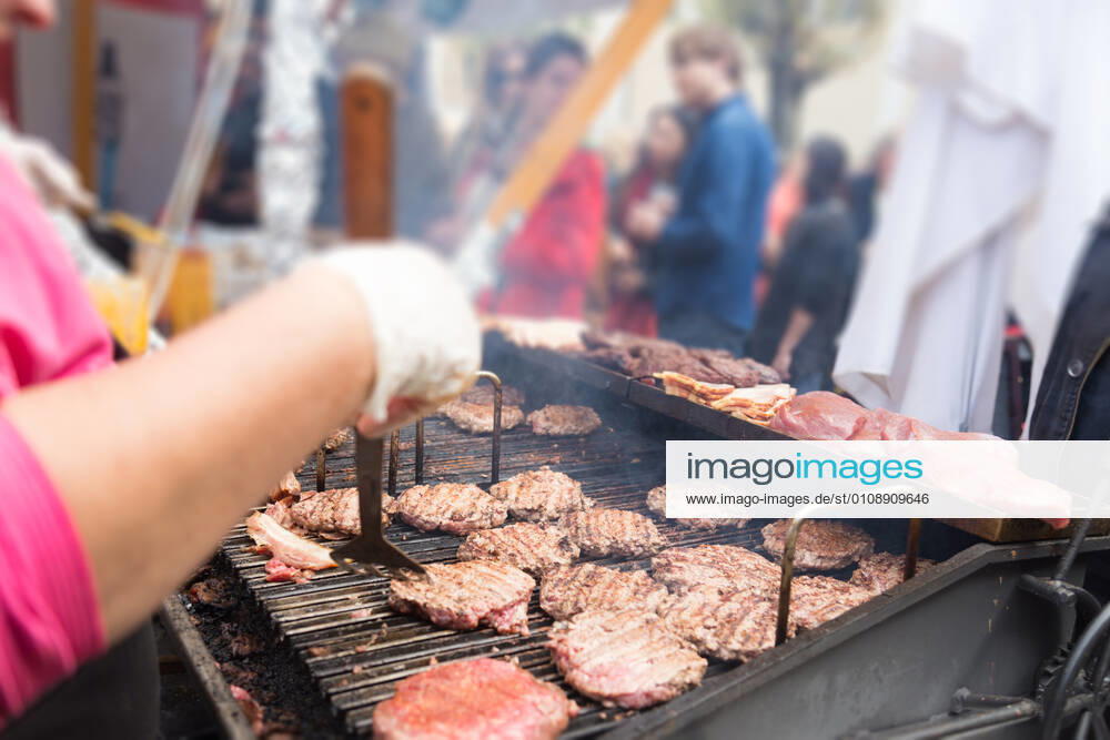 Beef burgers being grilled on food stall grill. Chef making beef burgers outdoor on open kitchen international food festival event. Street food ready to serve on a food stall.burger, grill, hamburger, street food, food, beef, stall, street, fast, meat, snack, outdoors, cuisine, seller, vendor, catering, lunch, meal, delicious, restaurant, junk food, sauce, outdoor, urban, event, making, chef, decorate, to go, take out, cart, plate, dressing, healthy, city, open kitchen, cheese, bacon, specialty, topping, pork, oven, stove, glove, fest,