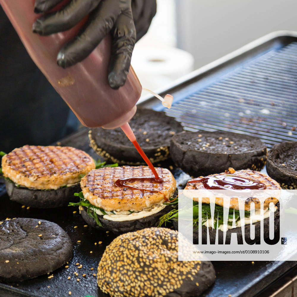 Beef burgers ready to serve on food stall. Chef making beef burgers outdoor on open kitchen international food festival event. Street food ready to serve on a food stall.burger, food, stall, hamburger, street, street food, beef, bun, fast, meat, snack, outdoors, cuisine, seller, vendor, catering, lunch, meal, delicious, restaurant, junk food, sauce, salad, outdoor, urban, event, making, chef, desk, decorate, tomatoes, sandwich, to go, take out, cart, grill, plate, dressing, ketchup, mayonnaise, lettuce, gloves, black, wholemeal, healthy, city, open kitchen,