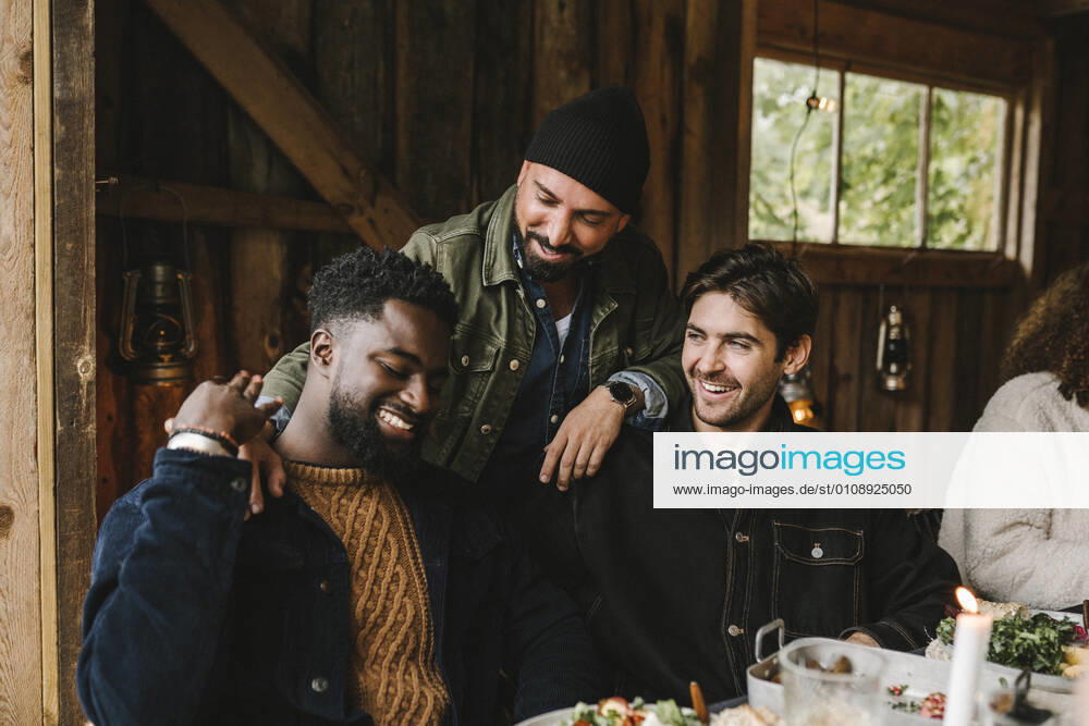 Smiling man talking to male friends at dinner party Sweden, Stockholm, model released, property released