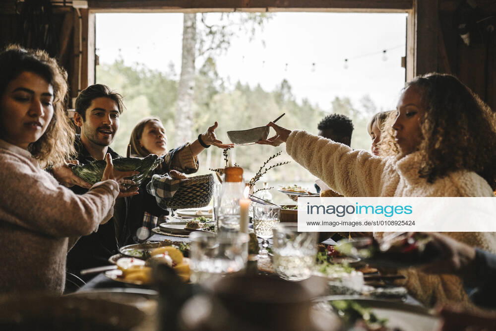 Female passing food bowl to friend over table during social event Sweden, Stockholm, model released, property released