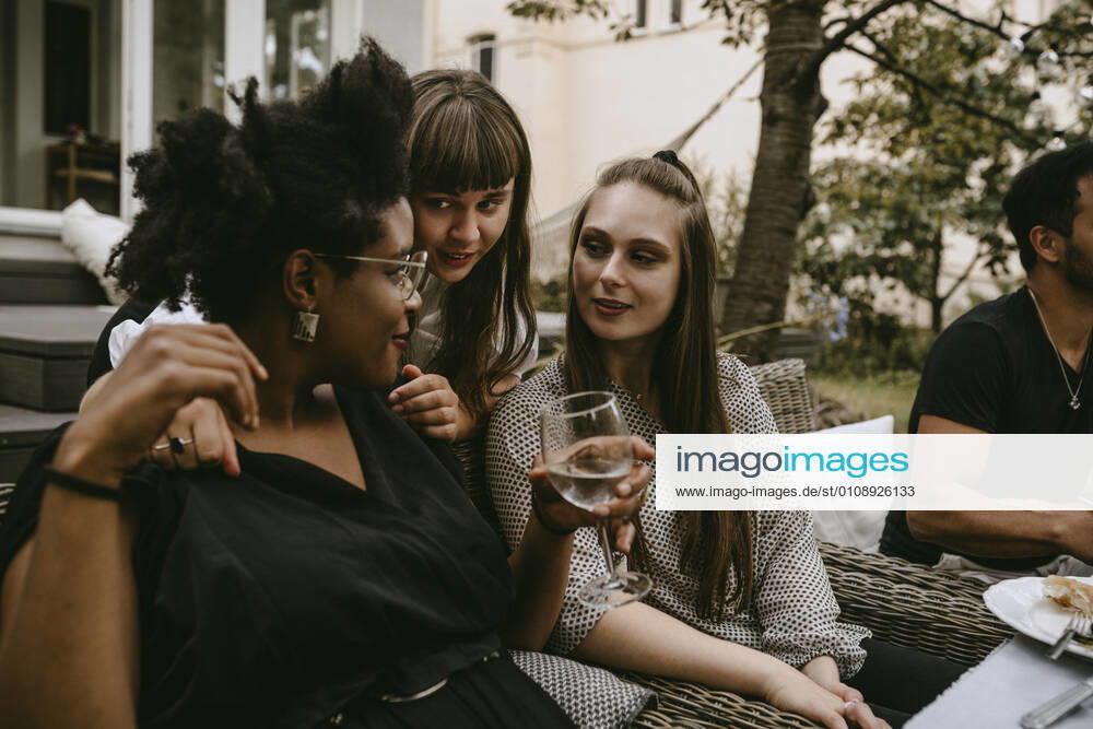 Smiling female friends talking while enjoying during garden party Sweden, Stockholm, model released, property released