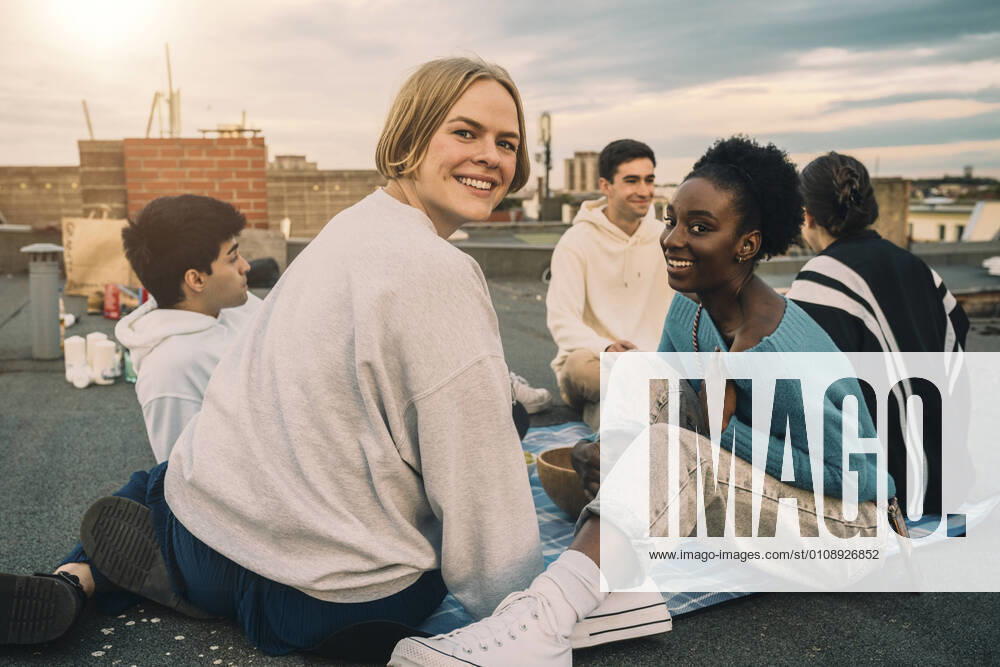 IMAGO Creative: Gesellschaft, Integration Portrait of female friends enjoying on building terrace during sunset Germany, Berlin, model released, property released