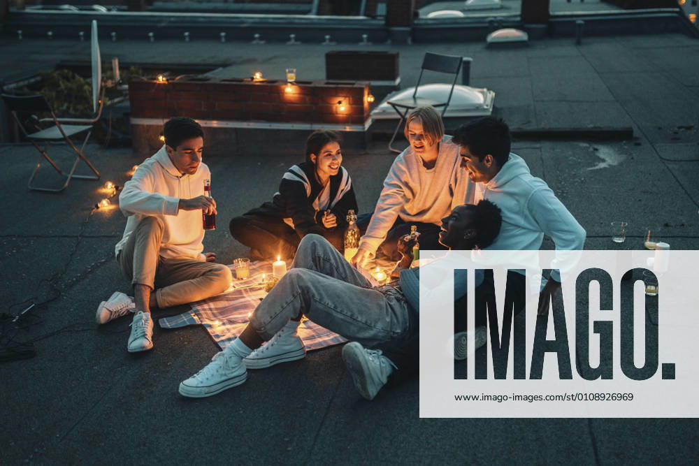IMAGO Creative: Jahreszeit Frühling, Picknick High angle view of male and female friends talking on building terrace during sunset Germany, Berlin, model released, property released