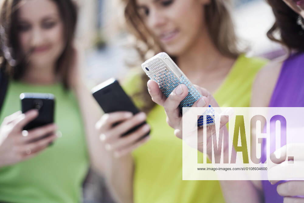 Female business colleagues using mobile phones for text messaging model released Symbolfoto property released AJOF00691