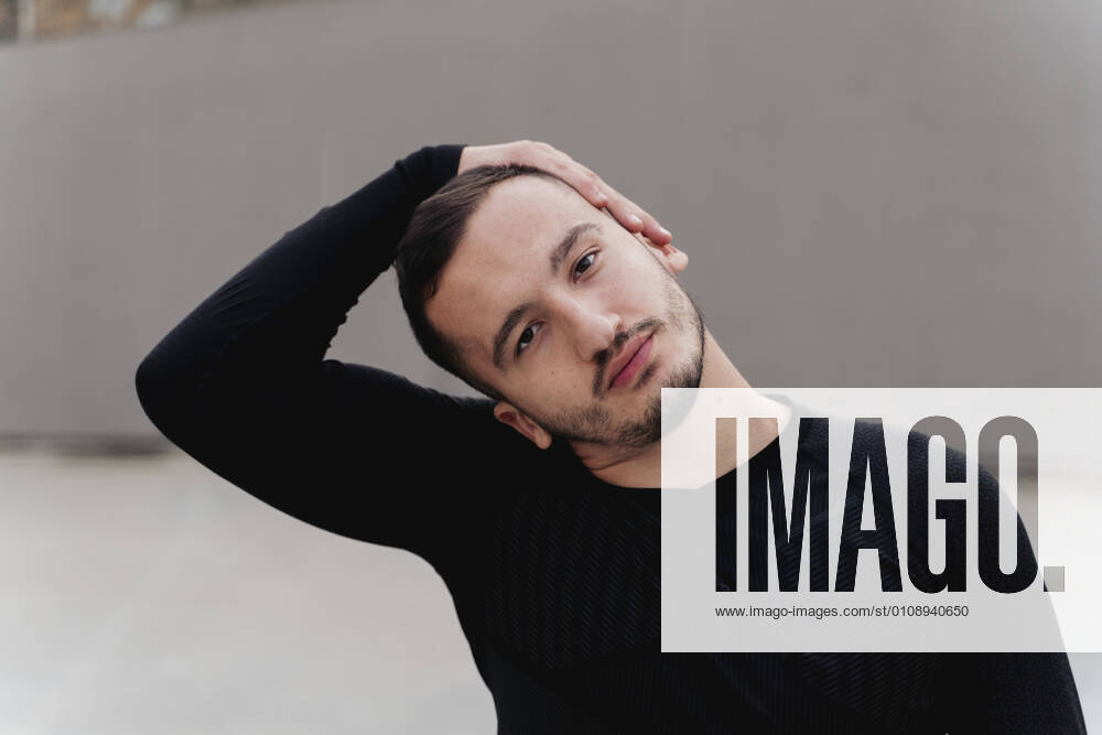 Man stretching head while standing against wall model released Symbolfoto FMOF01278