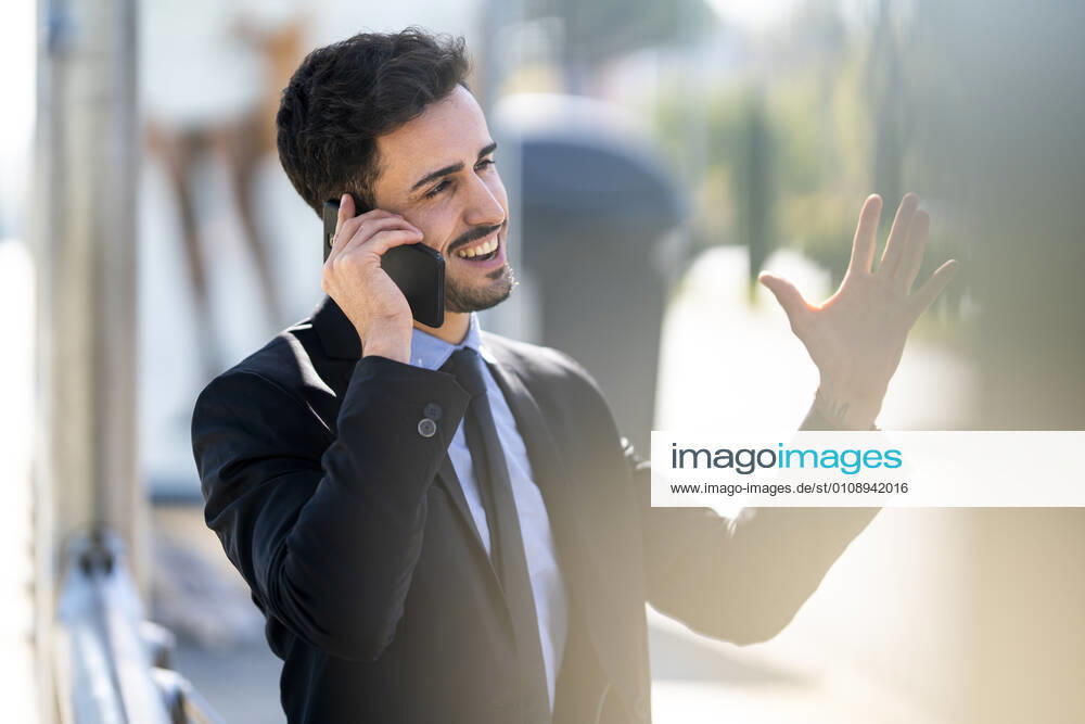 Smiling businessman gesturing while talking on mobile phone outdoors model released Symbolfoto GGGF00385