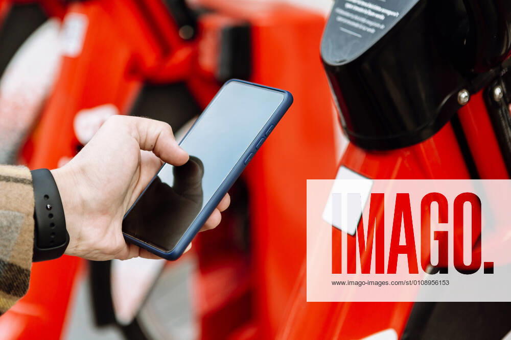 IMAGO Creative: Klimawandel - Zukunft und Innovation Mans hand holding smart phone to rent bicycle model released Symbolfoto XLGF00883