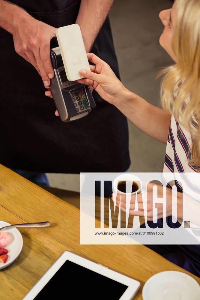 Woman paying with mobile payment Woman paying with mobile payment in the cafe, model released20s, Young Adult, Woman, Female, Caucasian, Man, Male, Cafe, Business, Coffee Shop, Cafeteria, Restaurant, Food And Drink Industry, Coffee House, Lifestyle, Leisure, Weekend Activities, City Life, Stylish, Fashionable, Style, Beautiful, Casual Clothing, Hip, Hipster, Fashion, Sitting, Table, Holding, Cup, Beverage, Coffee, Espresso, Smiling, Waiter, Service, Job, Work, Occupation, Profession, Apron, Smartphone, Mobile Phone, Wireless Technology, Phone, Touching, Using, Payment, Bill, Mobile Payment, Money Transfer, Money Exchange, Tablet Computer, Touchscreen, Digital Tablet, Tablet Pc, Tablet