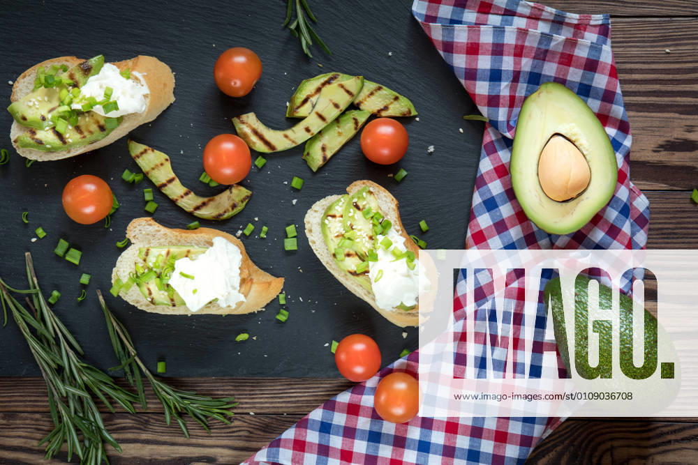Bread with slices of avocado and cream cheese Bread with slices of grilled avocado and cream cheese on a black cutting stone board. Fresh parsley and rosemary. Vegetarian, vegan concept.avocado, toast, cream, cheese, food, bread, sandwich, green, white, healthy, fruit, meal, vegetable, snack, gourmet, lunch, breakfast, appetizer, delicious, natural, fresh, health, diet, tasty, dinner, vegetarian, slice, eating, tomato, raw, burger, butty, calories, cooking, dark, dietary, dietetic, genetically, organic, seasonal, seeds, spoon, spring, summer, vegan, vegetables,