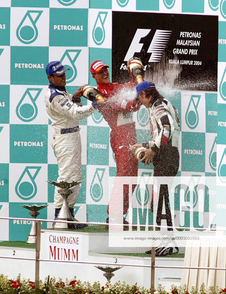 Siegerehrung GP Malaysia 2004 - v.li.: Juan Pablo Montoya (Kolumbien BMW-Williams) und Sieger Michael Schumacher (Deutschland Ferrari) verpassen Podiumsneuling Jenson Button (England BAR-Honda) die verdiente Sektdusche Motorsport Grand Prix Herren Großer Preis von Malaysia 2004, Formel 1 Weltmeisterschaft, F1, F, GP, WM Gruppe Sepang Kuala Lumpur Begeisterung, Freude,