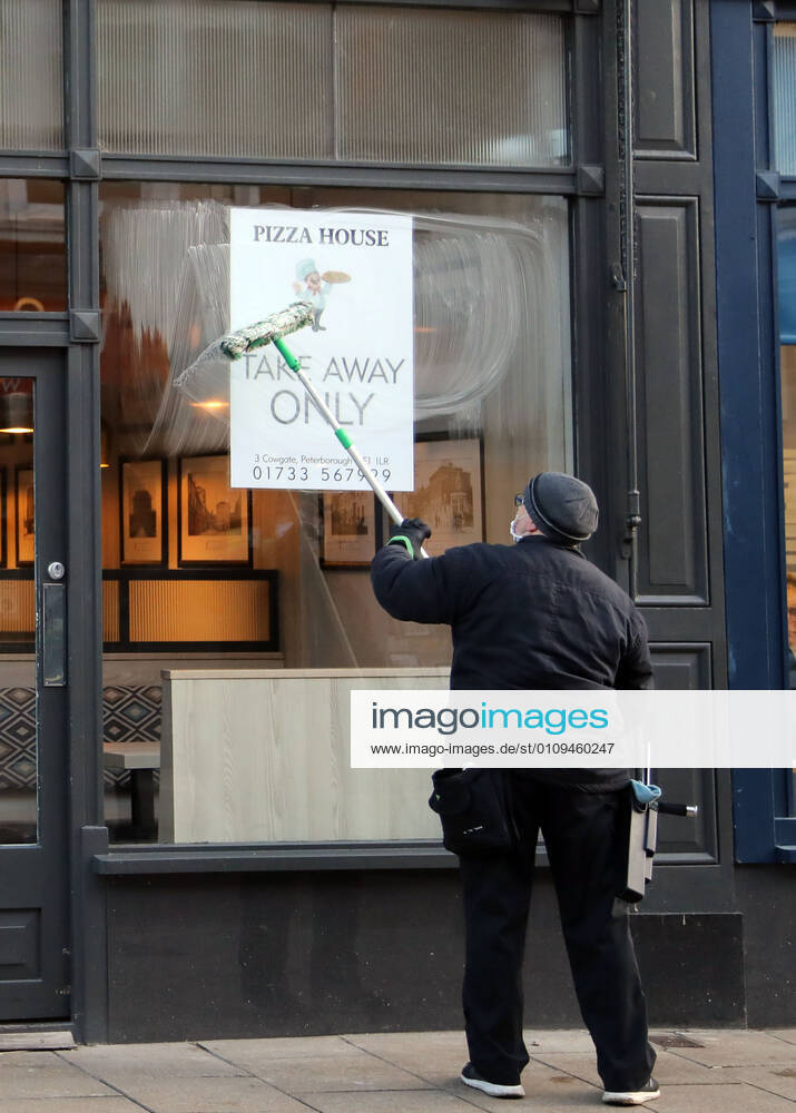 A window cleaner cleans the windows of the Pizza House restaurant which is now only open for take away meals, on the first day of Lockdown Three in Peterborough, Cambridgeshire. Prime Minister Boris Johnson last night announced there will be another national lockdown starting today, to help stop the spread of Coronavirus. Again, people are not allowed to leave home except for minimal food shopping, medical treatment, exercise - once a day, and essential work. COVID-19 Coronavirus third lockdown, Peterborough, Cambridgeshire, UK, on January 5, 2021