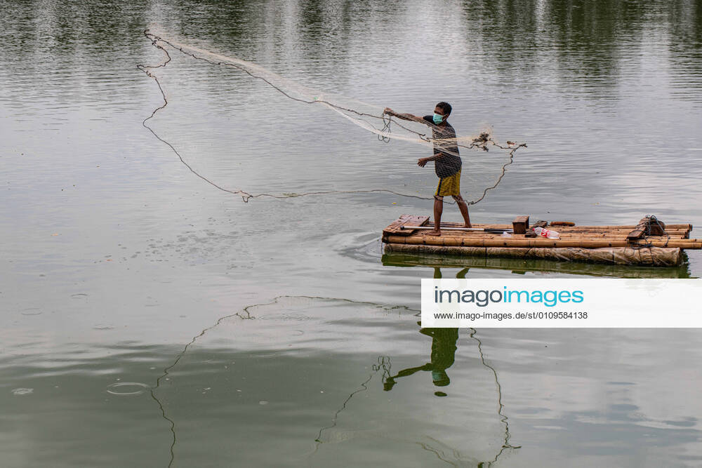 South Tangernag, Banten, Indonesia, 08 January 2021 : Fisherman with mask on activity fisihing at the lake using maskActivity of people at Situ Gintung Lake in Pandemic Era. Indonesia still have high Corona Virus Spreading and plan for Partial Lockdown of Java and Bali Island starting in January 11th 2021. South Tangerang Indonesia - ZUMAh128 20210108_zap_h128_001
