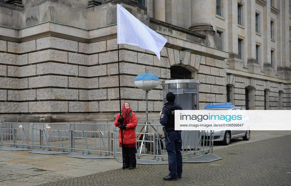 Berlin in the phase of the coronavirus crisis, in the picture woman with flag in front of the Reichstag, it voted against the third law for the protection of the population in an epidemic situation of national scope and the names of 235 members of the Bundestag who voted against the law, right a policeman, 08 01 2021,