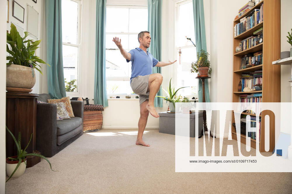 Mature man balancing on leg while standing at home model released Symbolfoto property released PMF01461