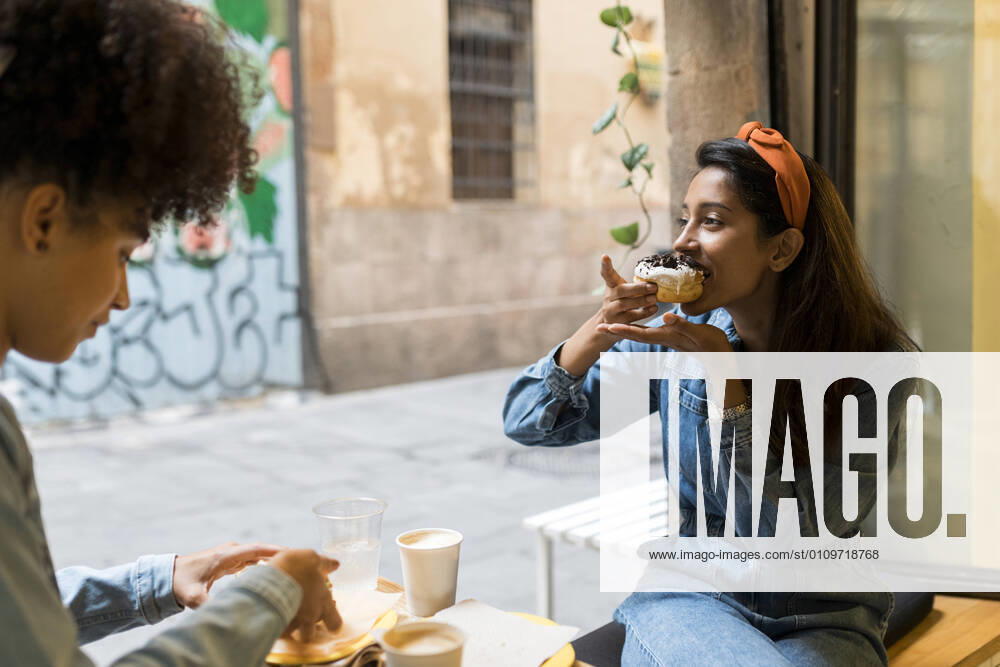Friends eating food while sitting by window at cafe model released Symbolfoto property released VABF03923