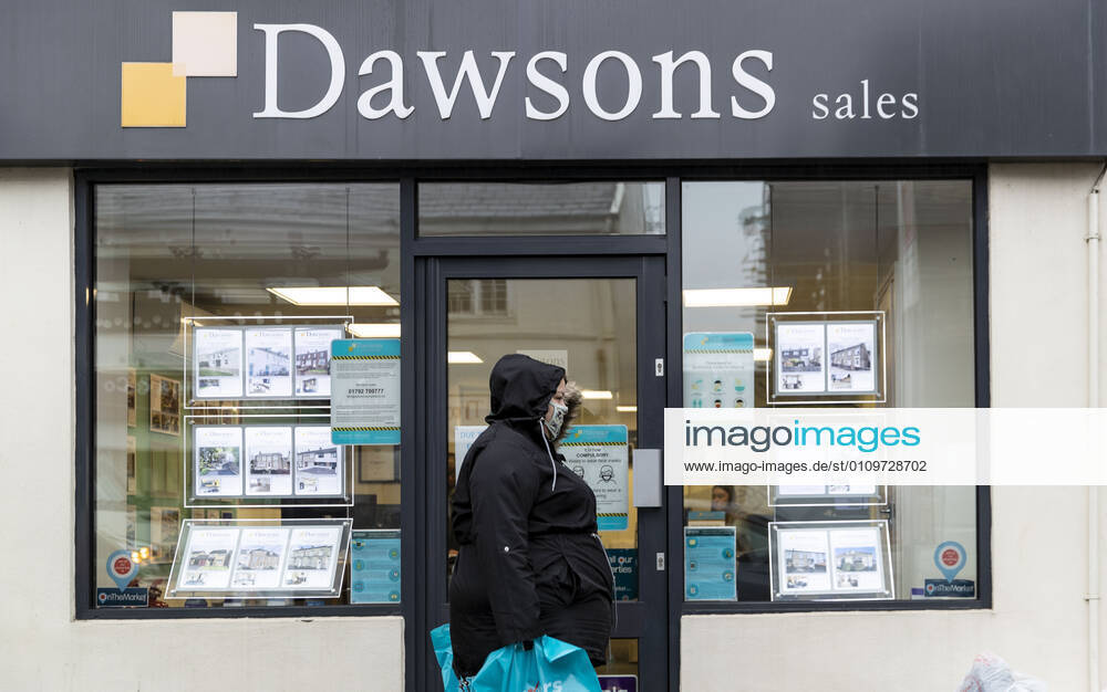A woman wearing a face mask walks past Dawsons property agent in Wales. Newport United Kingdom - ZUMAs197 20210111_zab_s197_015