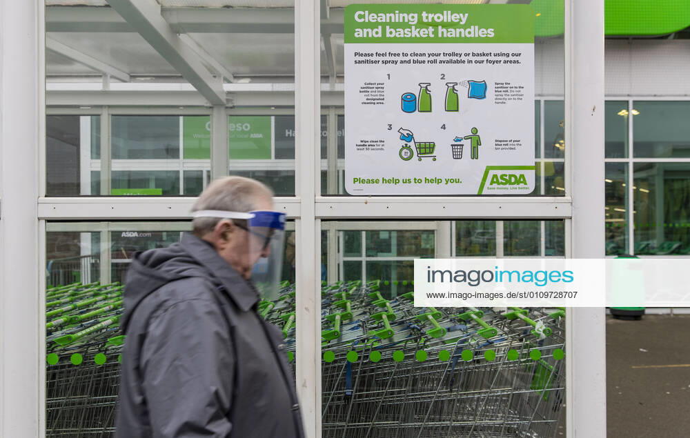 A man wearing a face mask walks pass Covid19 sign outside ASDA supermarket in Wales. Newport United Kingdom - ZUMAs197 20210111_zab_s197_019