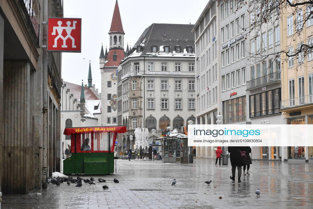 Theme picture Winter in the Coronavirus Pandemic Prolongation Lockdown until 31 January 2021 Empty streets and squares Only a few passers-by go over the Marienplatz in Munich on 12 01 2021 At a hot chestnut stand pigeons cavort persons, passers-by