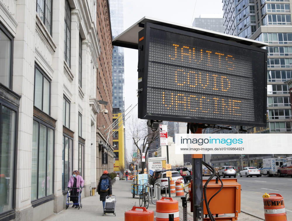 Pedestrians walk by a sign that says Javits Covid Vaccine one block from the Jacob K. Javits Convention Center,in New York City on Wednesday, January 13, 2021. The Javits Convention Center which served as a massive field hospital last spring when New York City was the epicenter of the pandemic, now will serve as a huge vaccine distribution center. NYP20210113199 JohnxAngelillo