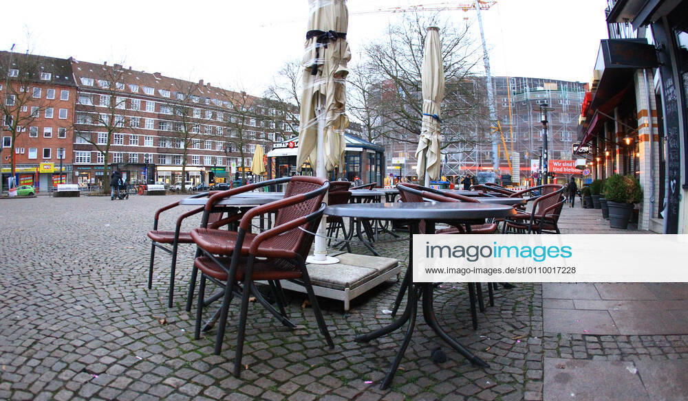 Chairs stacked on top of each other stand in front of a closed restaurant on the deserted Winterhuder Marktplatz in Hamburg Winterhude Hamburg