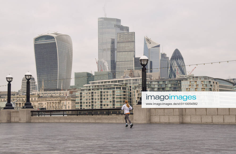 A woman jogs next to the Thames with the City of London skyline in the background..England remains under lockdown as the government battles to keep the coronavirus pandemic under control. London United Kingdom - ZUMAs197 20210115_zab_s197_008
