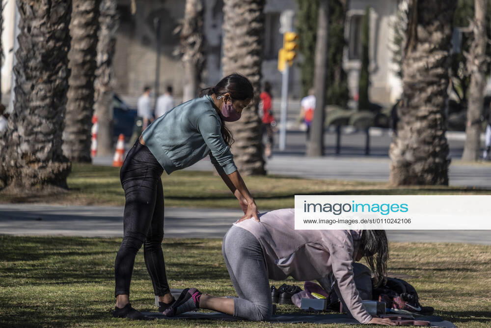 Two people wearing sportswear are seen stretching in the garden area of the Plaza de la Rosa de los Vientos..With public sports centers and gyms closed due to the increase in Covid-19 infections, many individual and social sports activity is taking place in public space such as open areas near the beaches. Barcelona Spain - ZUMAs197 20210117_zaa_s197_067