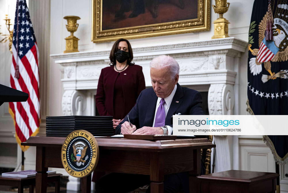 U.S. President Joe Biden signs an executive order after speaking during an event on his administration s Covid-19 response with U.S. Vice President Kamala Harris, left, in the State Dining Room of the White House in Washington, D.C., U.S., on Thursday, Jan. 21, 2021. Biden in his first full day in office plans to issue a sweeping set of executive orders to tackle the raging Covid-19 pandemic that will rapidly reverse or refashion many of his predecessor s most heavily criticized policies Washington USA - ZUMAs152 20210121_zaa_s152_155
