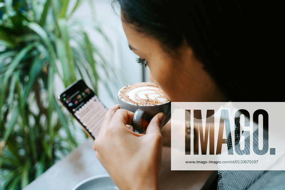 Woman drinking a cup of coffee and using mobile, Model released