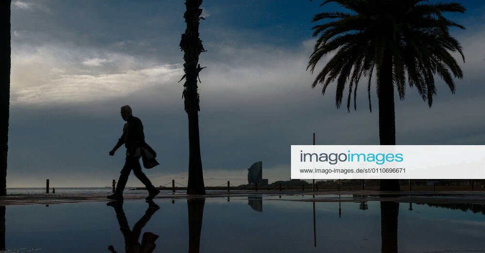 A commuter walks at Barcelona s nearly deserted beach after a rainy storm. Barcelona Spain - ZUMAo105 20210122_zap_o105_001