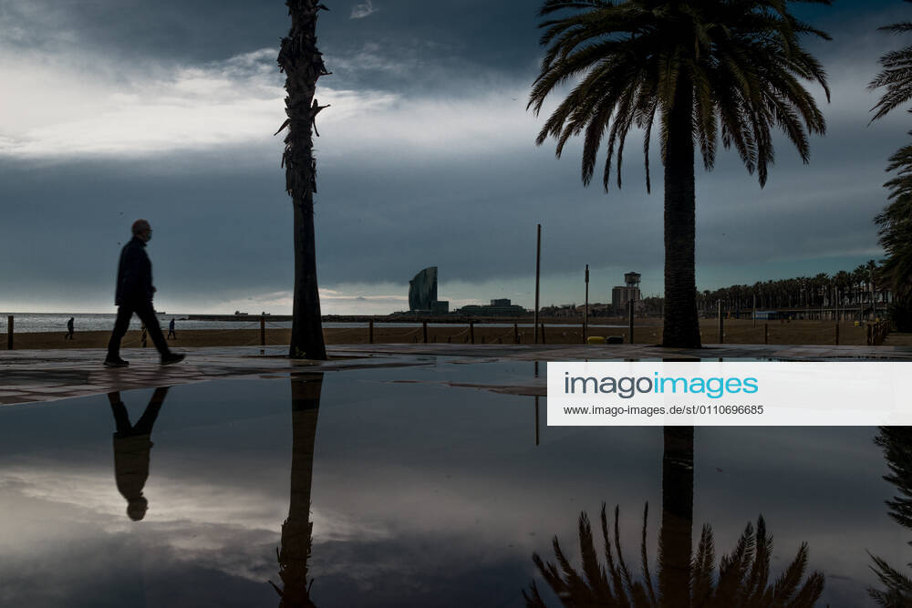 A commuter walks at Barcelona s nearly deserted beach after a rainy storm. Barcelona Spain - ZUMAo105 20210122_zap_o105_002