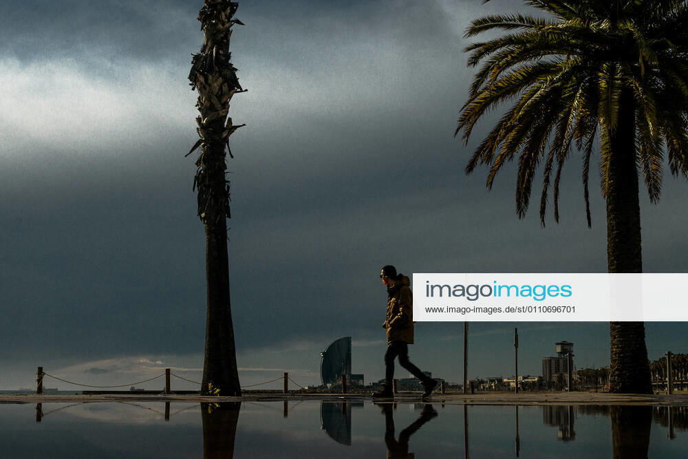 A commuter walks at Barcelona s nearly deserted beach after a rainy storm. Barcelona Spain - ZUMAo105 20210122_zap_o105_004