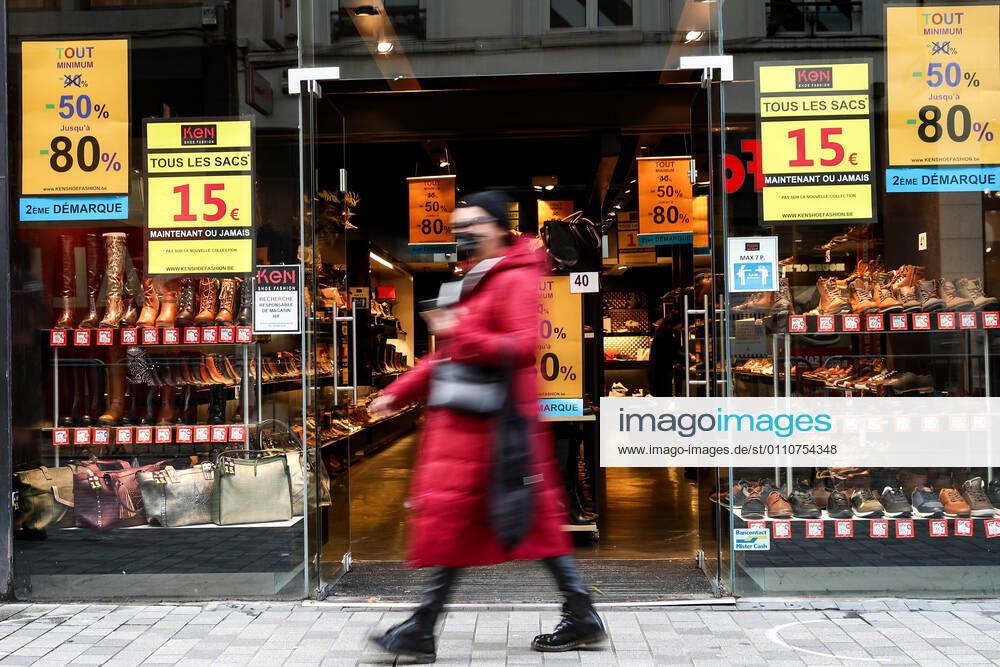 (210123) -- BRUSSELS, Jan. 23, 2021 -- A woman wearing a face mask walks past a shop with sales posters in Brussels, Belgium, Jan. 22, 2021. The annual Belgian winter sales kicked off on Jan. 4. To boost consumption, the scheduled four-week-long winter sales have been extended by two weeks until Feb. 15. ) BELGIUM-BRUSSELS-COVID-19-WINTER SALES ZhangxCheng