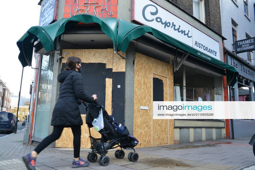 Woman wearing a face mask with a stroller walks past a closed and boarded up restaurant, near Waterloo Station during the third national lockdown..Prime Minister Boris Johnson announced that there was evidence that the new variant of the coronavirus is more deadly. London United Kingdom - ZUMAs197 20210123_zaa_s197_142