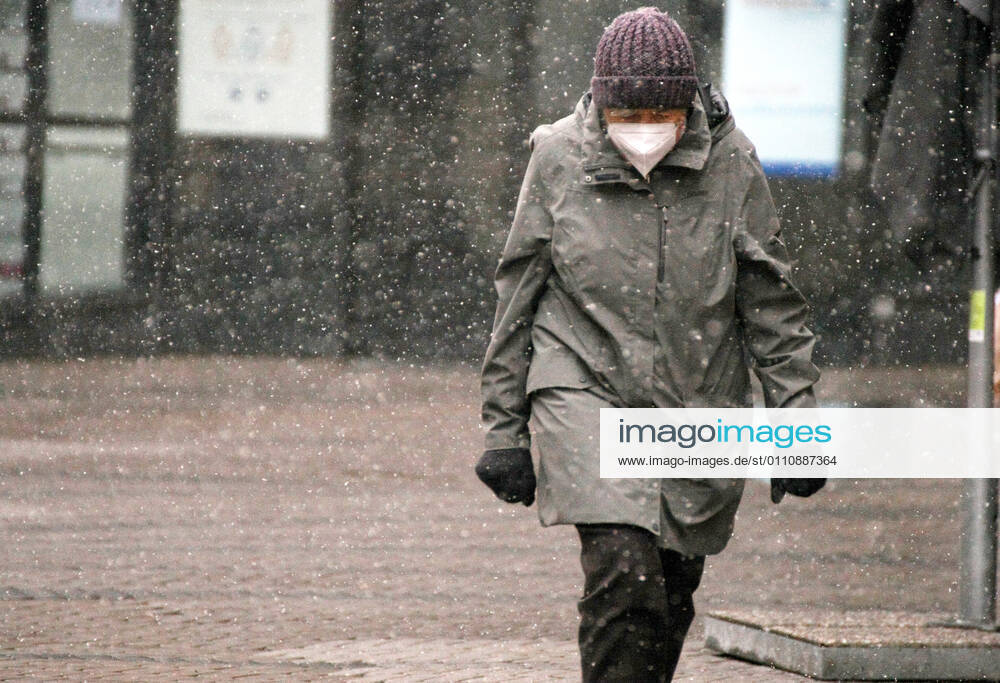 Winter wetter mit Schnee , an old women with Safety mask FFP2 is seen under the snow during the Hard Lockdown of the Covid 19 Coronavirus Pandemie in Nuremberg Nurnberg , Bayern , Deutschland . January 24 , 2021.