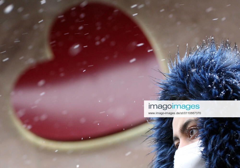 Winter wetter mit Schnee , herz , Saint Valentine , a women with Safety mask FFP2 is seen under the snow during the Hard Lockdown of the Covid 19 Coronavirus Pandemie in Nuremberg Nurnberg , Bayern , Deutschland . January 24 , 2021.