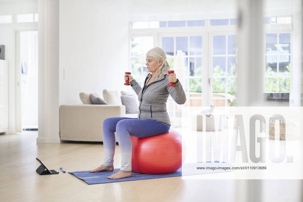 Senior woman exercising while learning from online tutorial through digital tablet at home model released Symbolfoto property released JAHF00062
