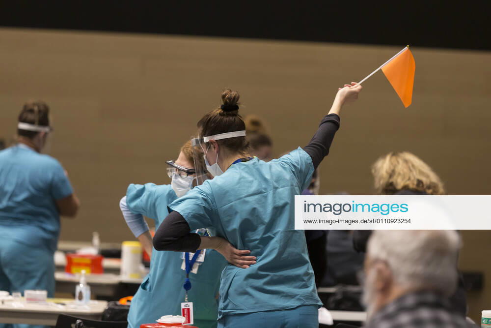 A medical worker waves a flag to notify the next patient at a pop up COVID-19 vaccine clinic at the Amazon Headquarters in Seattle on Sunday, January 24, 2021. Amazon partnered with Virginia Mason Franciscan Health to vaccinate 2,000 Washingtonians who currently qualify to be vaccinated under the stateâ€⠢s COVID-19 Vaccine Phases guidelines. Seattle USA - ZUMAg235 20210124_zap_g235_019