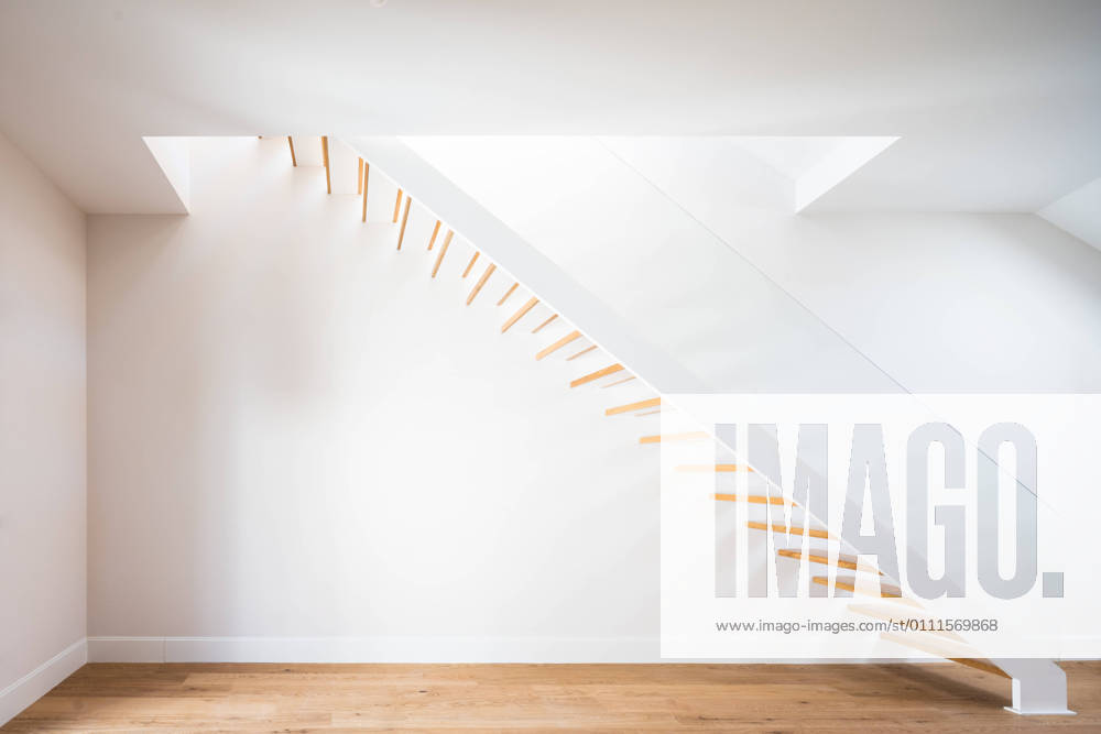 Wooden staircase above parquet near white wall with shadow in contemporary building in daylight