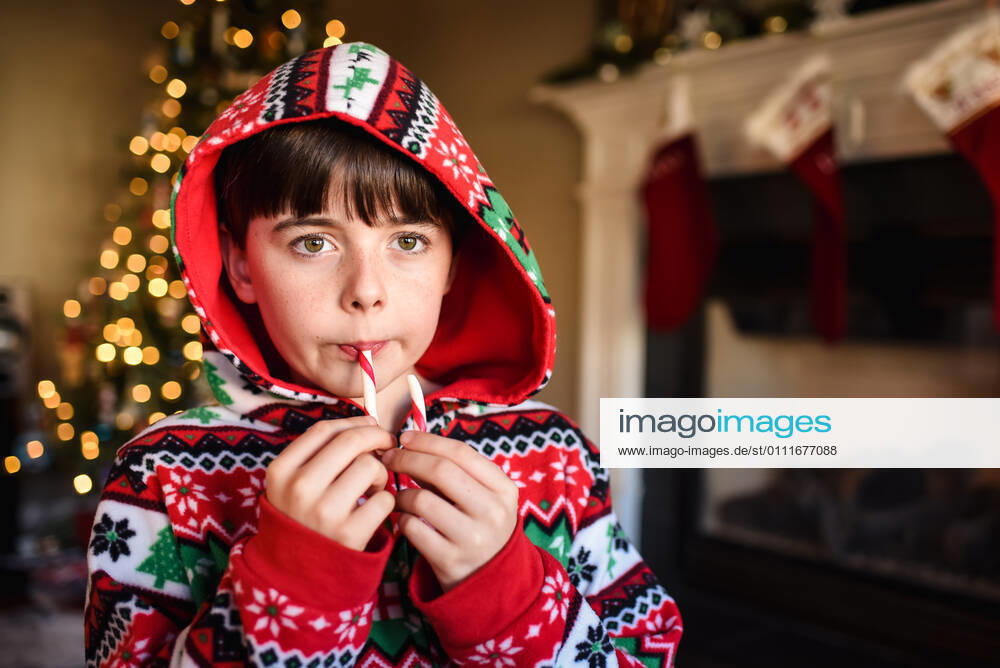 Cute boy in festive pajamas eating a candy cane at Christmas time. Kingston, ON, Canada CR_DOHO210113K-607764-01 ,model released, Symbolfoto
