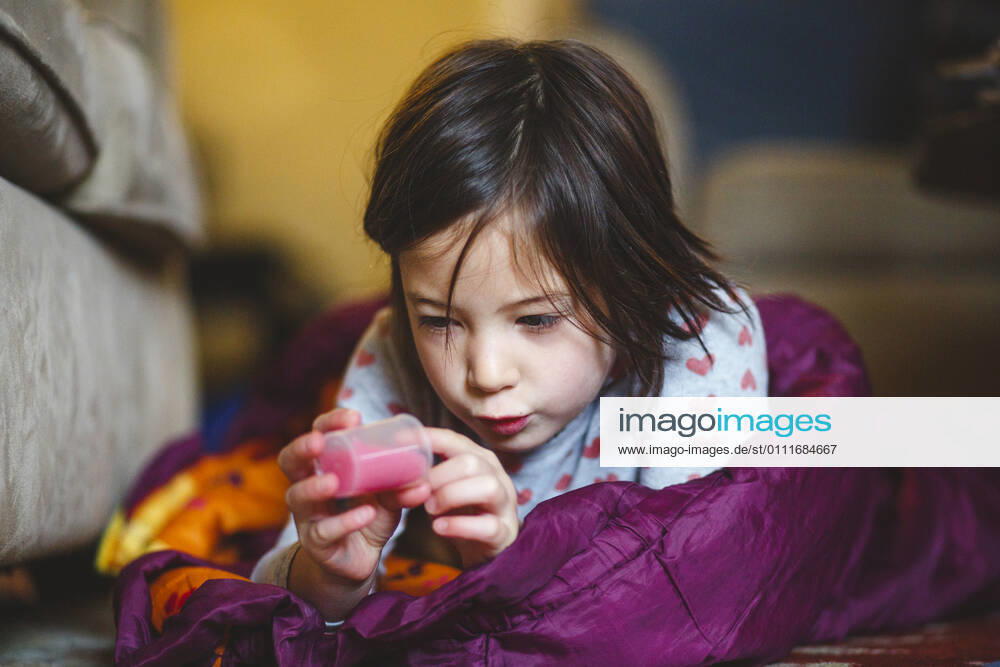 A little girl lays on floor in sleeping bag studying a tube of liquid Columbus, OH, United States CR_RETI210114-575732-01 ,model released, Symbolfoto