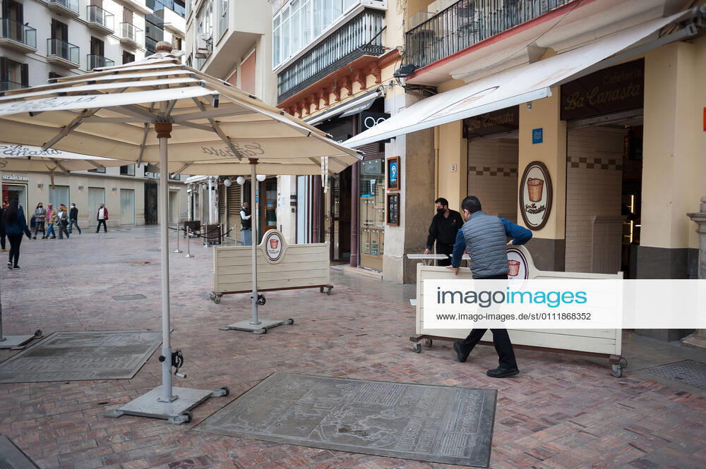 Workers seen lifting boards to close a coffee shop at an empty Plaza de la constitucion square amid the partial lockdown caused by coronavirus pandemic. Malaga Spain - ZUMAs197 20210203_zab_s197_019