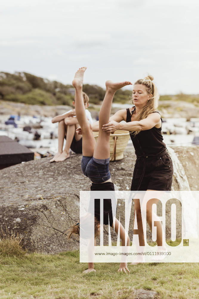 IMAGO Creative, Jahreszeit Sommer, Sommerferien IMAGO Creative: Dichotomien, Generationen Mother helping daughter to do handstand on land at harbor Sweden, Gothenburg, model released