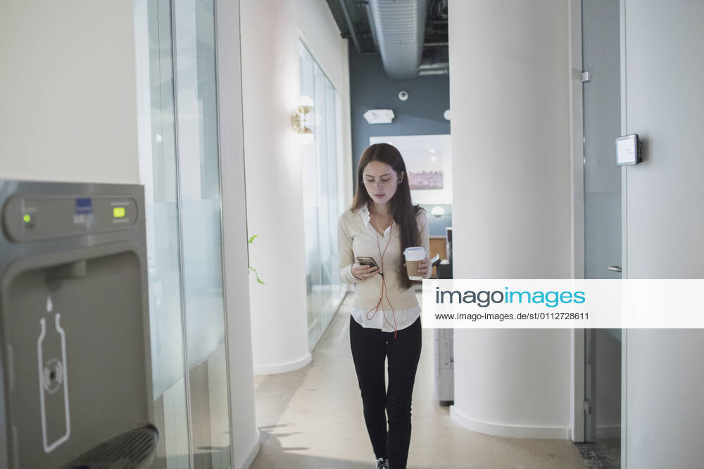 Young woman having a conversation on her smart phone holding a coffee cup in an office. model release HEX17003_TP_9410